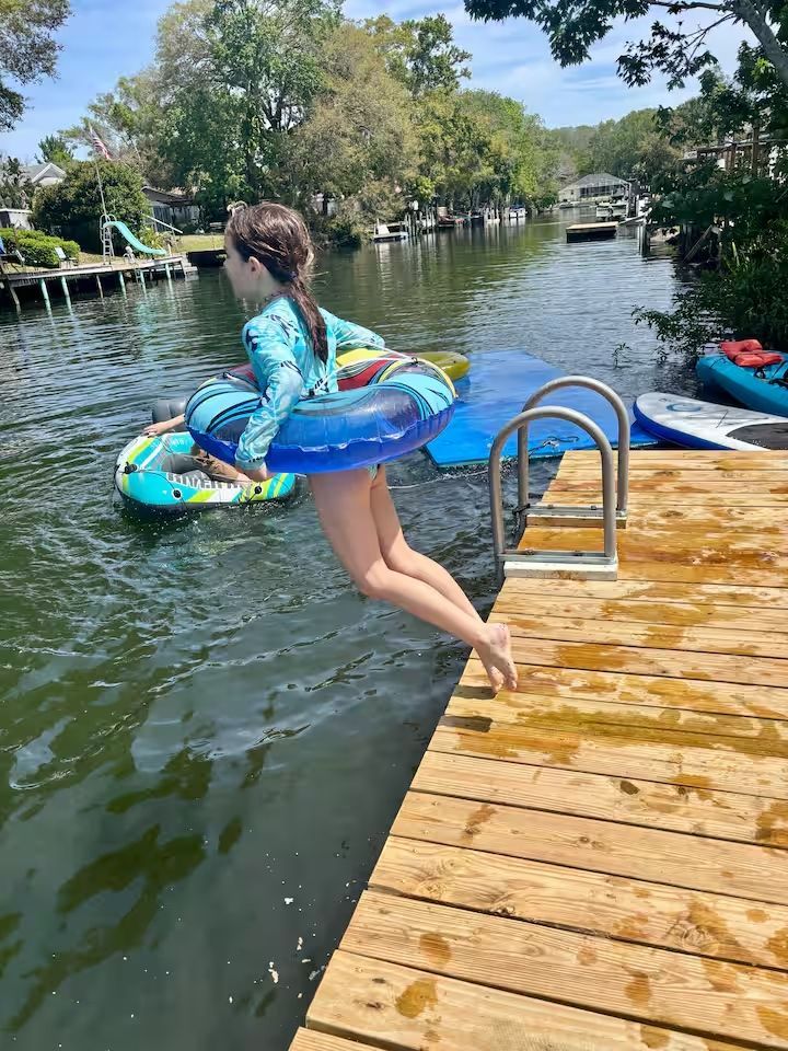 A little girl is jumping into the water from a dock.