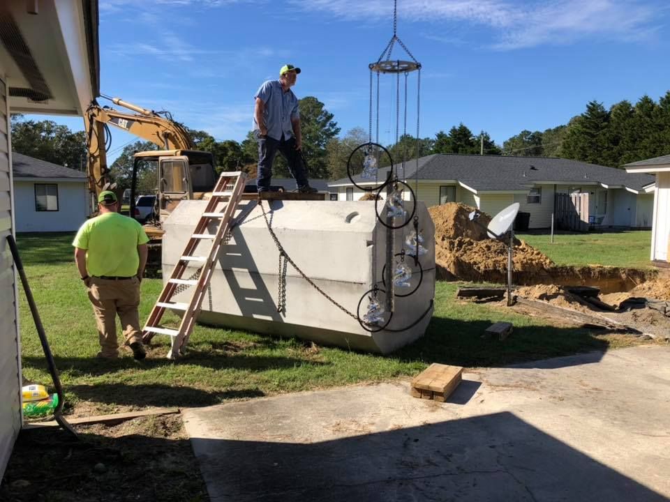 A man is standing on a ladder next to a large tank being lifted by a crane.