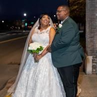 Bride and groom smiling outdoors at night, standing together in wedding attire