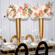 Elegant dining table with gold centerpieces and white, peach floral arrangements