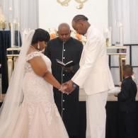 Bride and groom hold hands at the altar during a wedding ceremony.