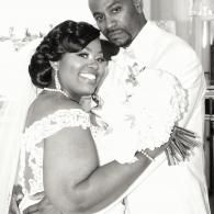 Two people in white wedding attire smiling and posing together indoors