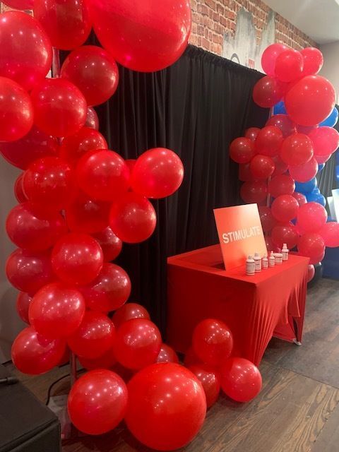Red balloon arch framing a red table with a sign at an indoor event entrance