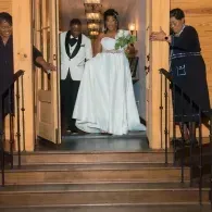 Bride and groom exiting a church at night, with guests standing by the open doors