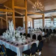 Elegant banquet hall with long white tablecloths, black chairs, and a chandelier