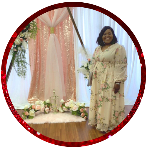 Woman smiling beside floral wedding backdrop with pink drapes and white flowers in a decorated room
