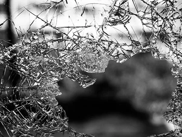 A black and white photo of a broken glass window