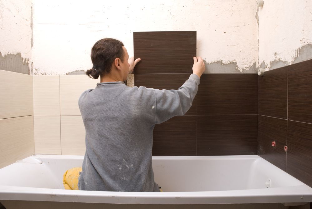 Person Tiling a Bathroom Wall — Platinum Kitchens & Bathrooms in Nambucca Heads, NSW