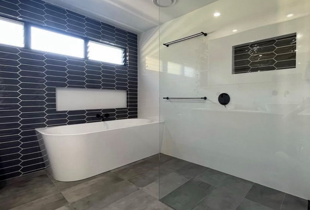Modern bathroom with a white tub, black tile wall, and glass shower — Platinum Kitchens & Bathrooms in North Boambee Valley, NSW