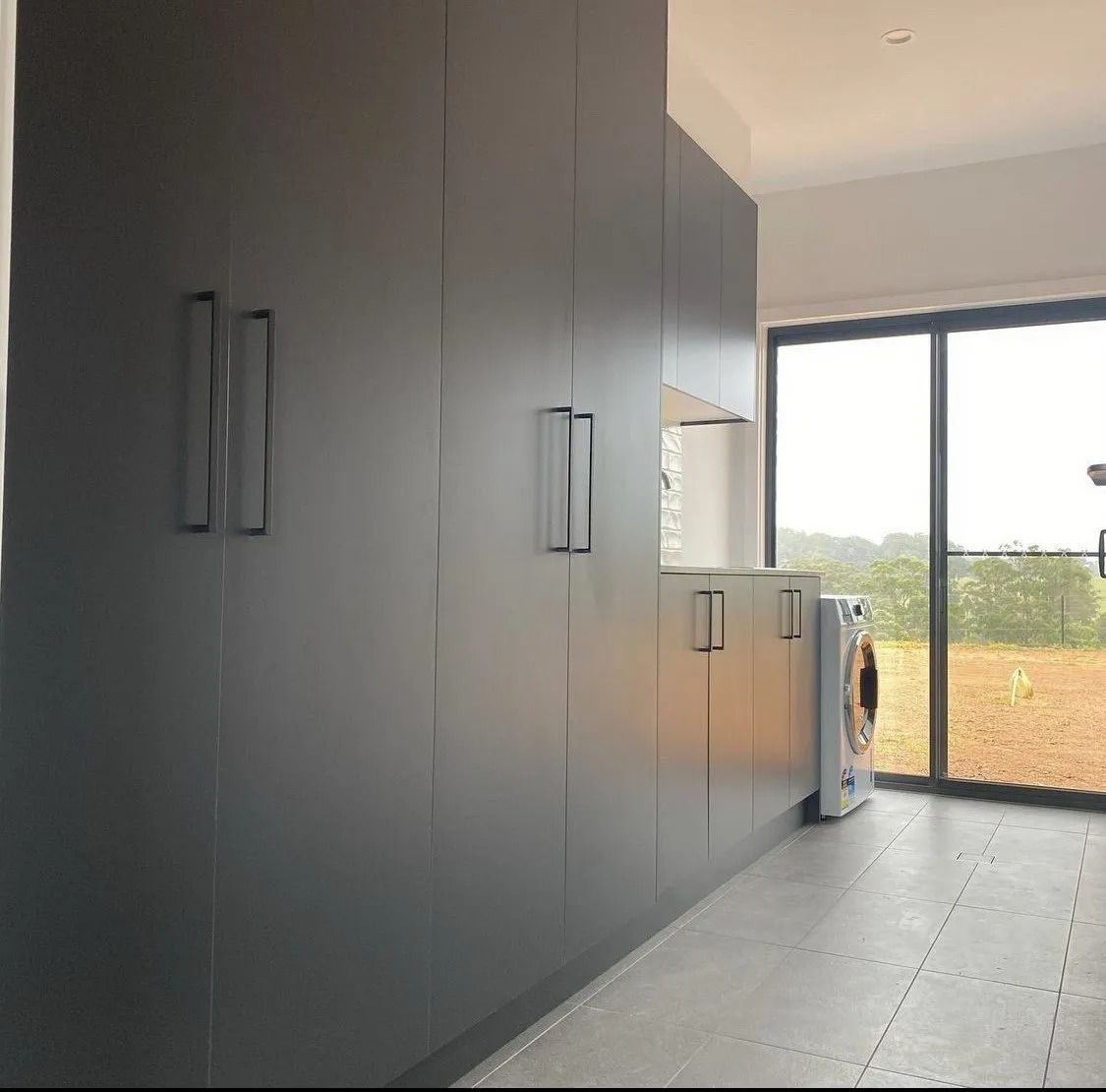 Dark Gray Cabinets with Black Handles in a Laundry Room — Platinum Kitchens & Bathrooms in Bonville, NSW