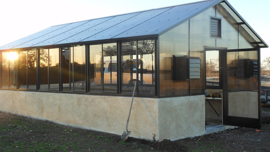 A greenhouse with a shovel in front of it.