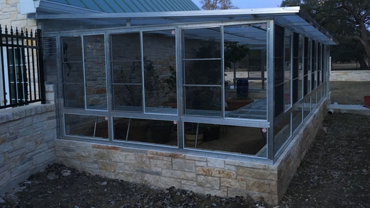 A screened in porch with lots of windows and a green roof.