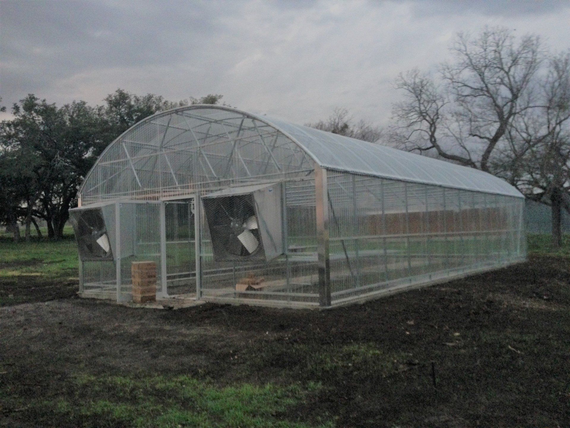 A greenhouse is sitting in the middle of a field.