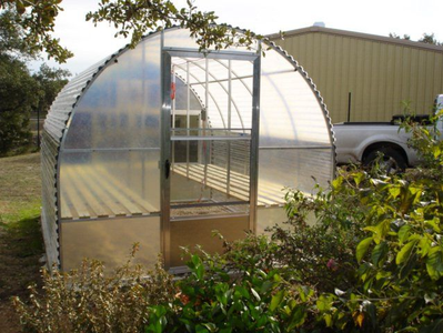 A greenhouse with a truck parked in front of it.