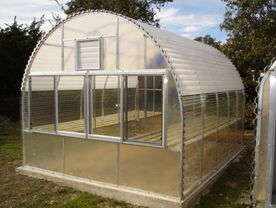 A greenhouse with a curved roof and lots of windows.