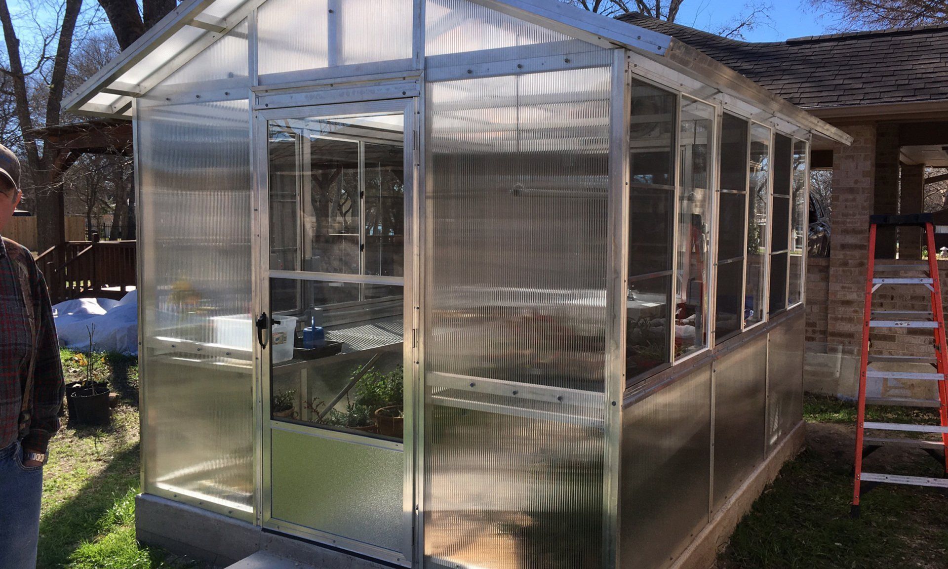 A greenhouse is being built in the backyard of a house.