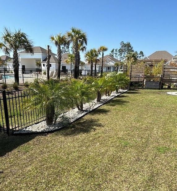 A lush green yard with palm trees and a fence.