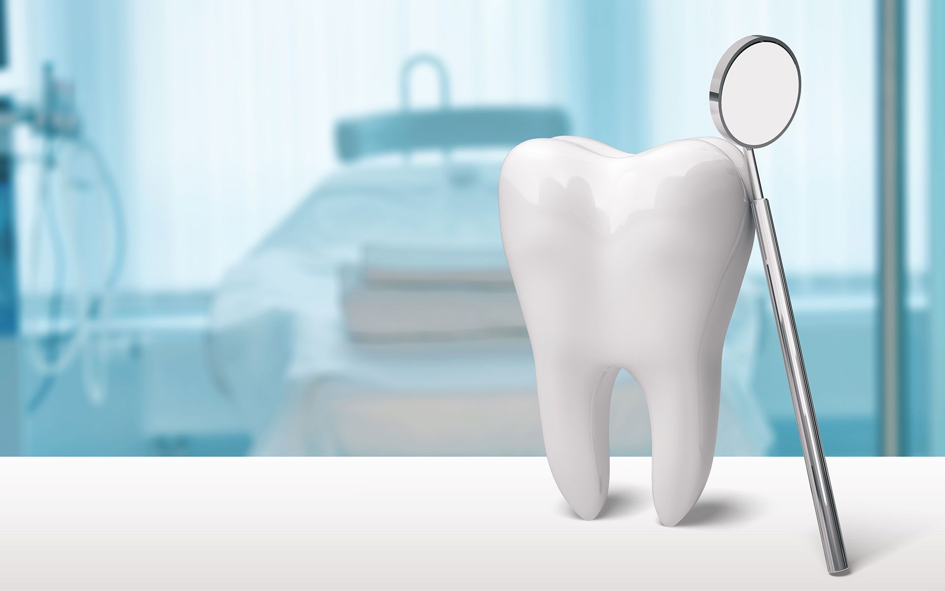 White tooth model and dental mirror on a table in a dentist's office.