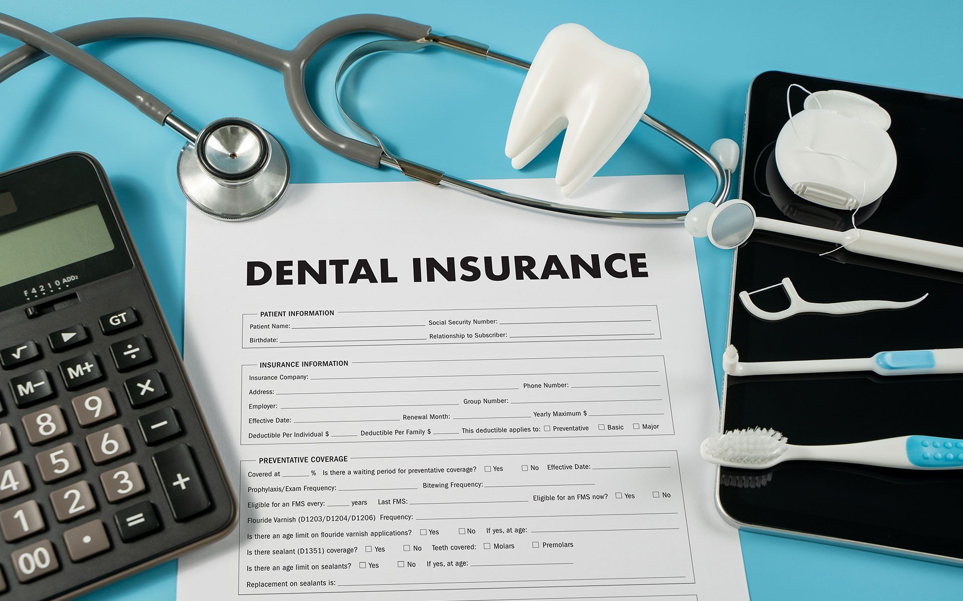 Dental insurance form with calculator, stethoscope, tooth model, and dental hygiene tools.