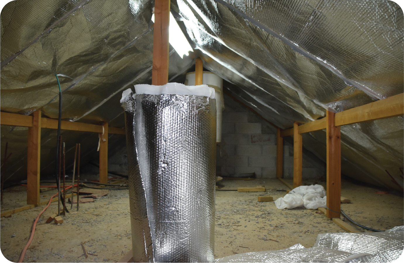 An attic with a pipe covered in aluminum foil