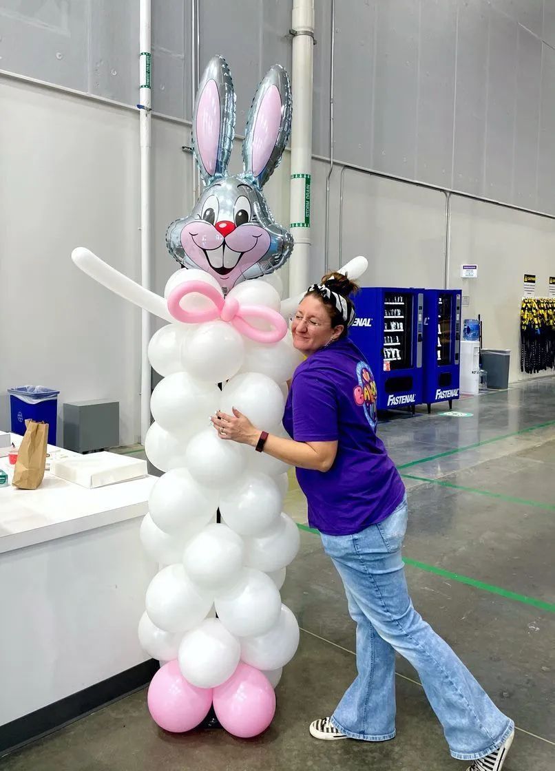 a woman is standing next to a bunny made out of balloons