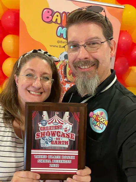 A man and a woman are holding a plaque that says greatest showcase on earth