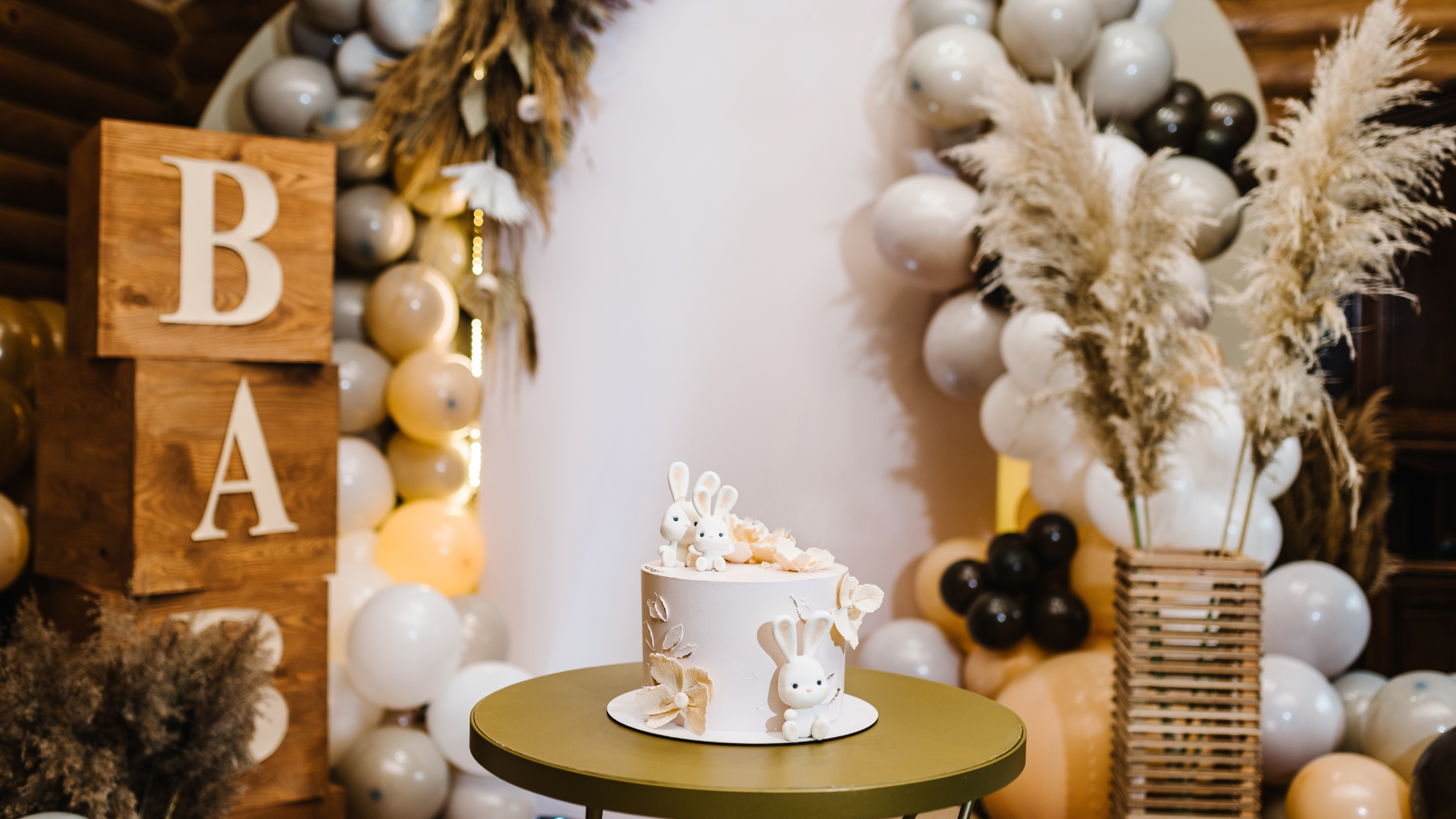 There is a cake on a table in front of balloons with baby shower decorations surrounding them.