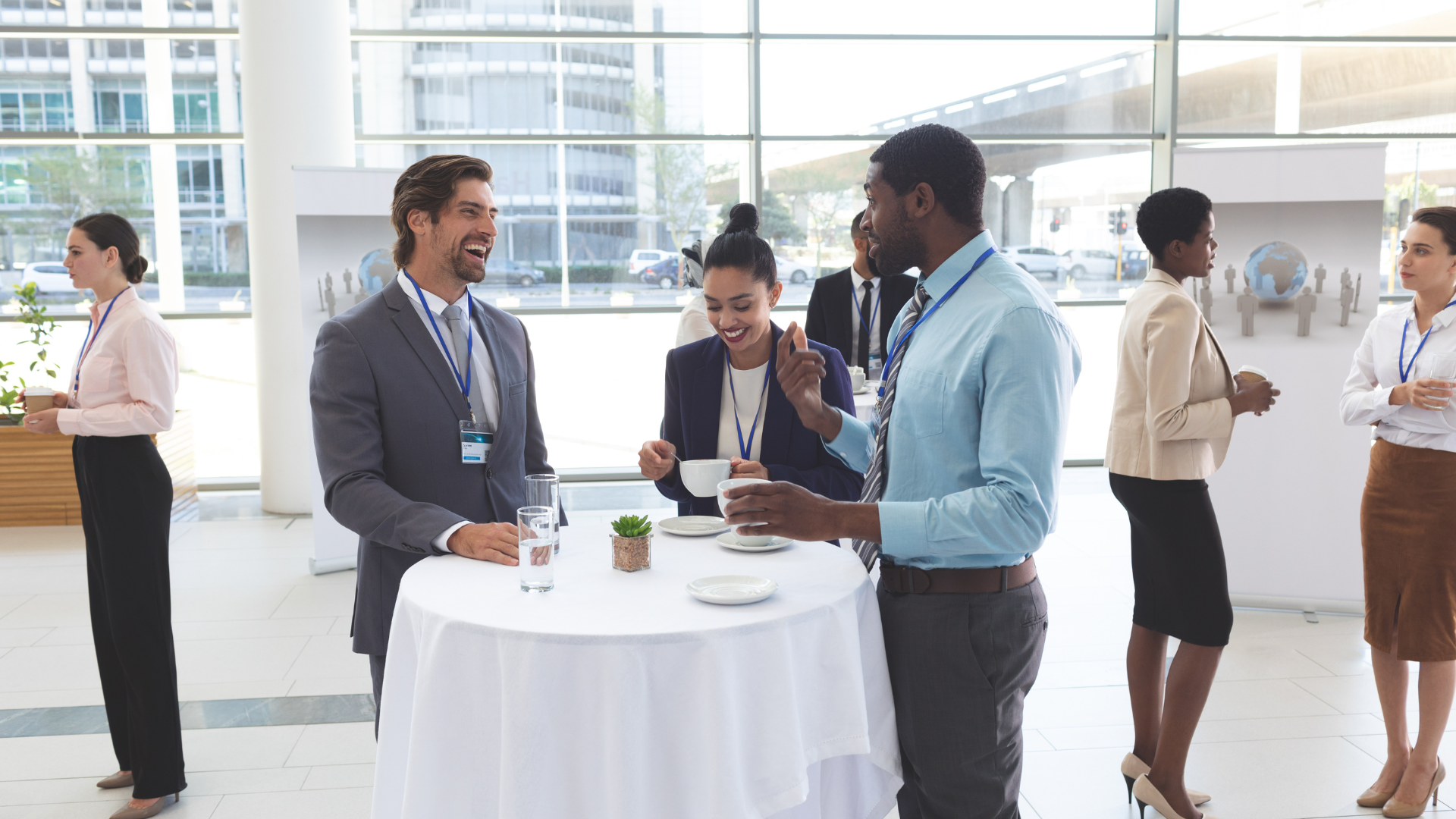 A group of business people are standing around a table talking to each other.