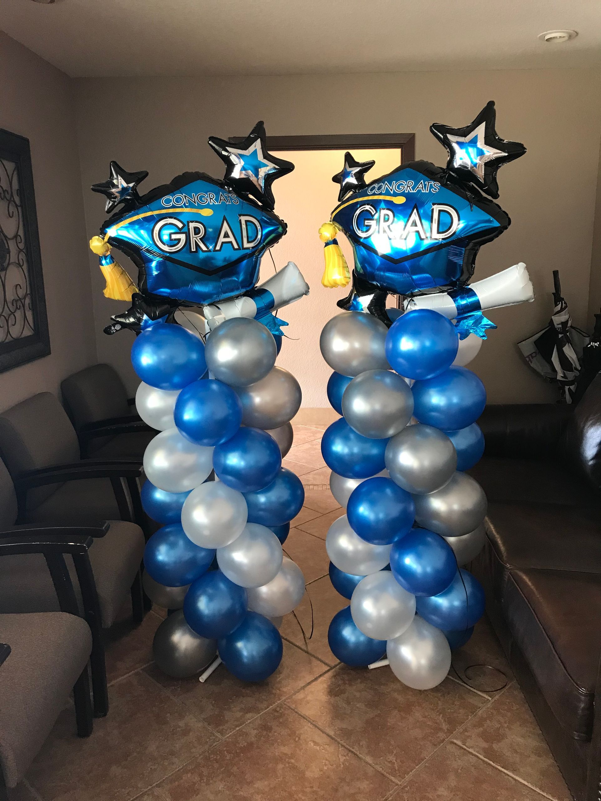 Two balloon columns topped with graduation cap balloons are in an office.