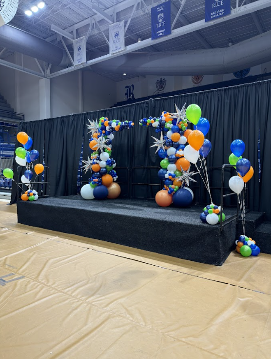 A balloon arch with starbursts is sitting on a stage. 