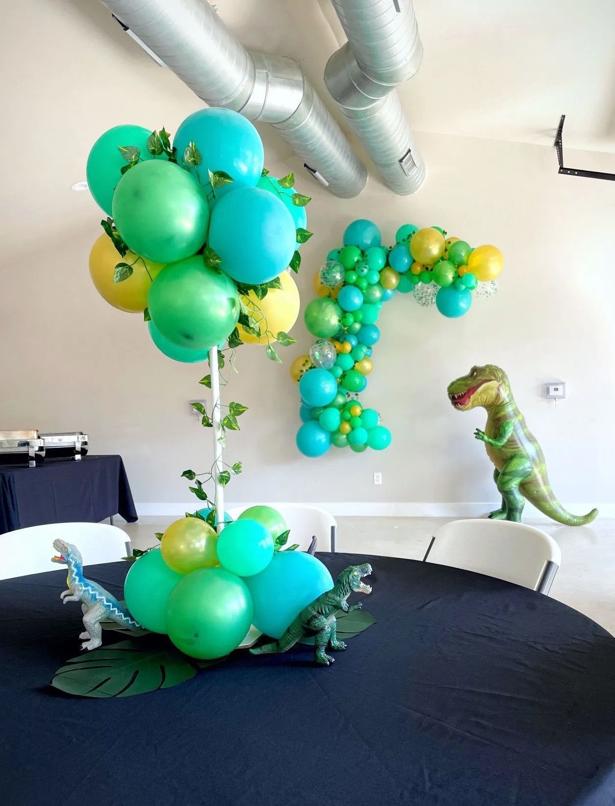 A table with balloons and a dinosaur on it.