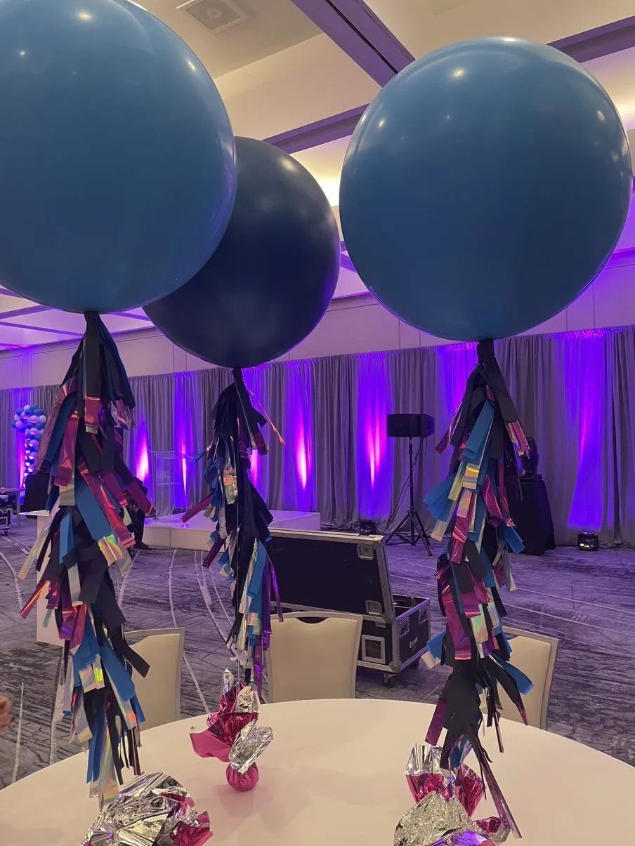 Two blue balloons are sitting on top of a table in a room.