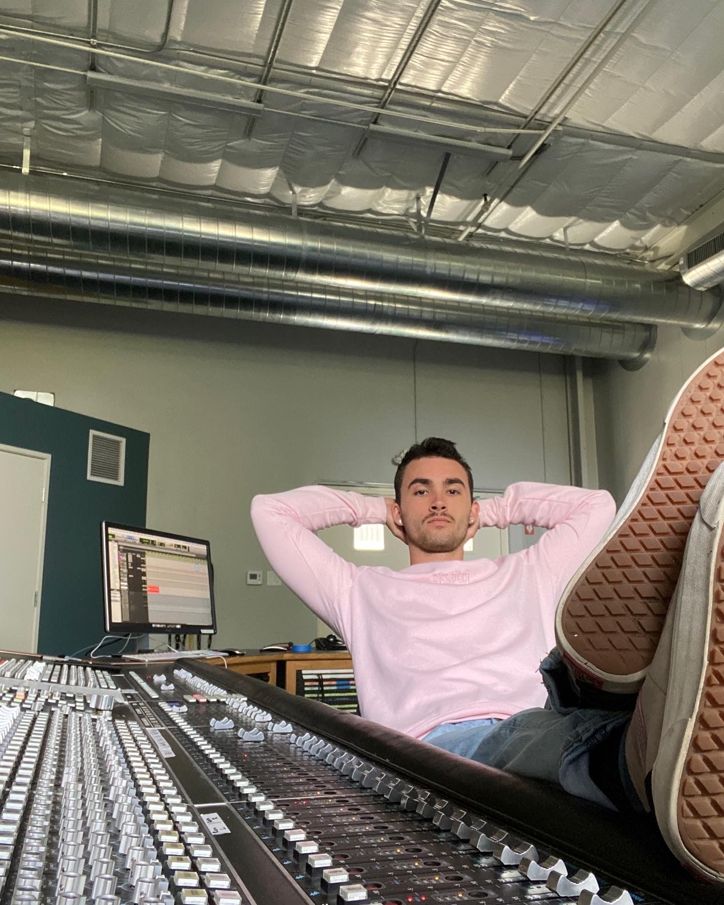 A man is sitting on a mixer with his feet up.