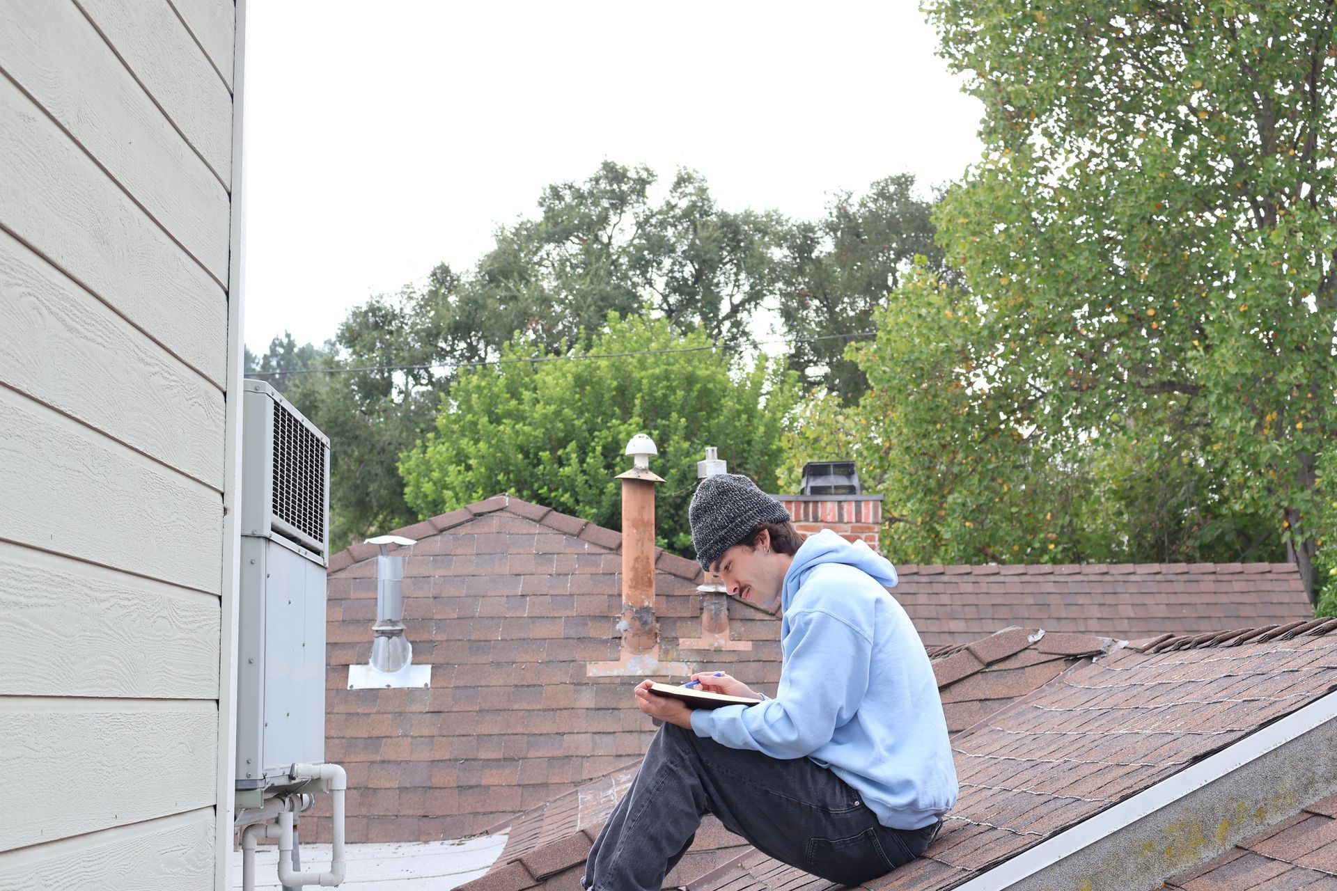 A man is sitting on the roof of a building reading a book.