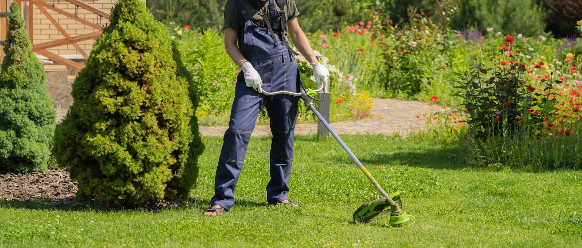 Un uomo sta usando un tosaerba per tagliare l'erba in un giardino.