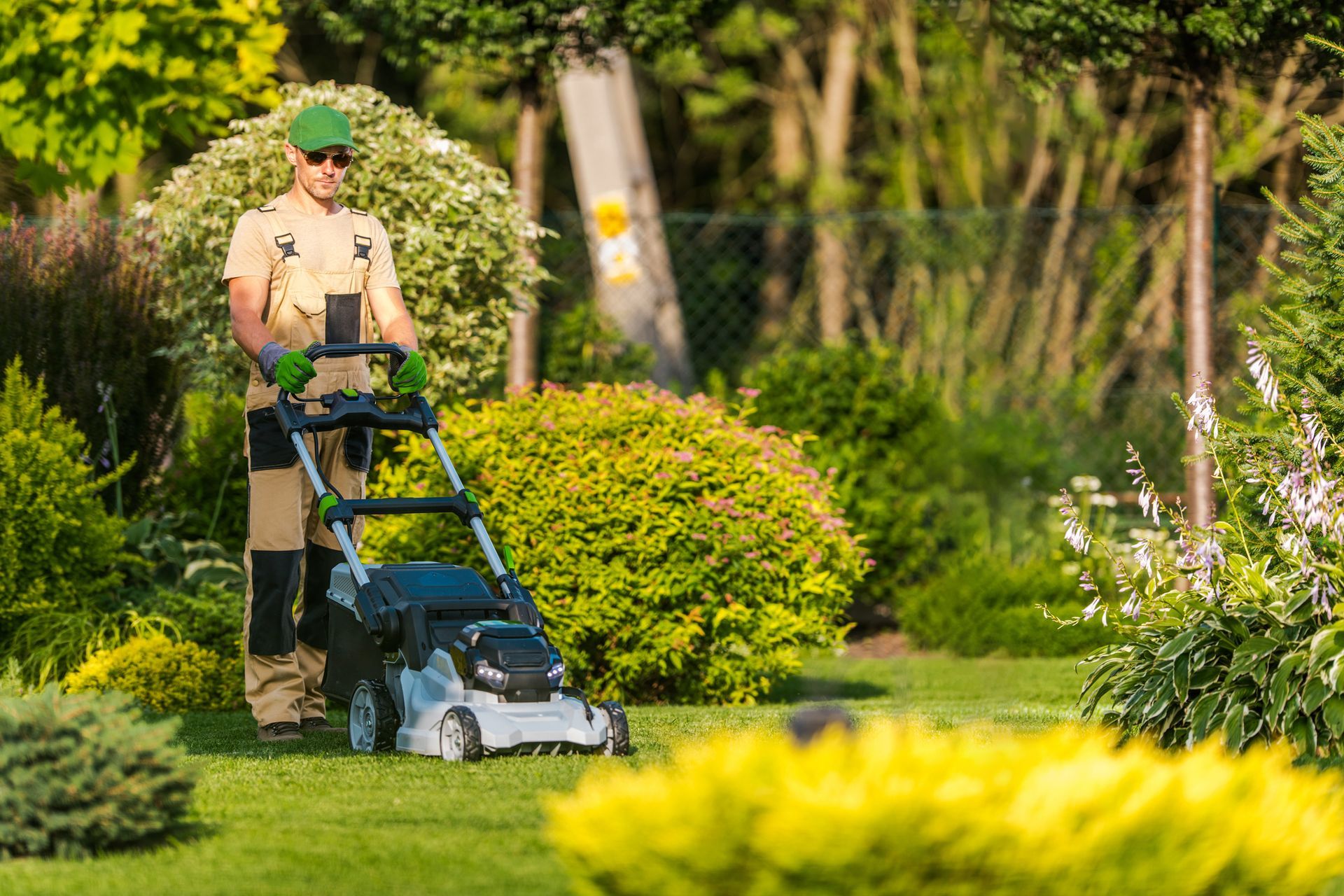 Un uomo sta usando un tosaerba per tagliare l'erba in un giardino.