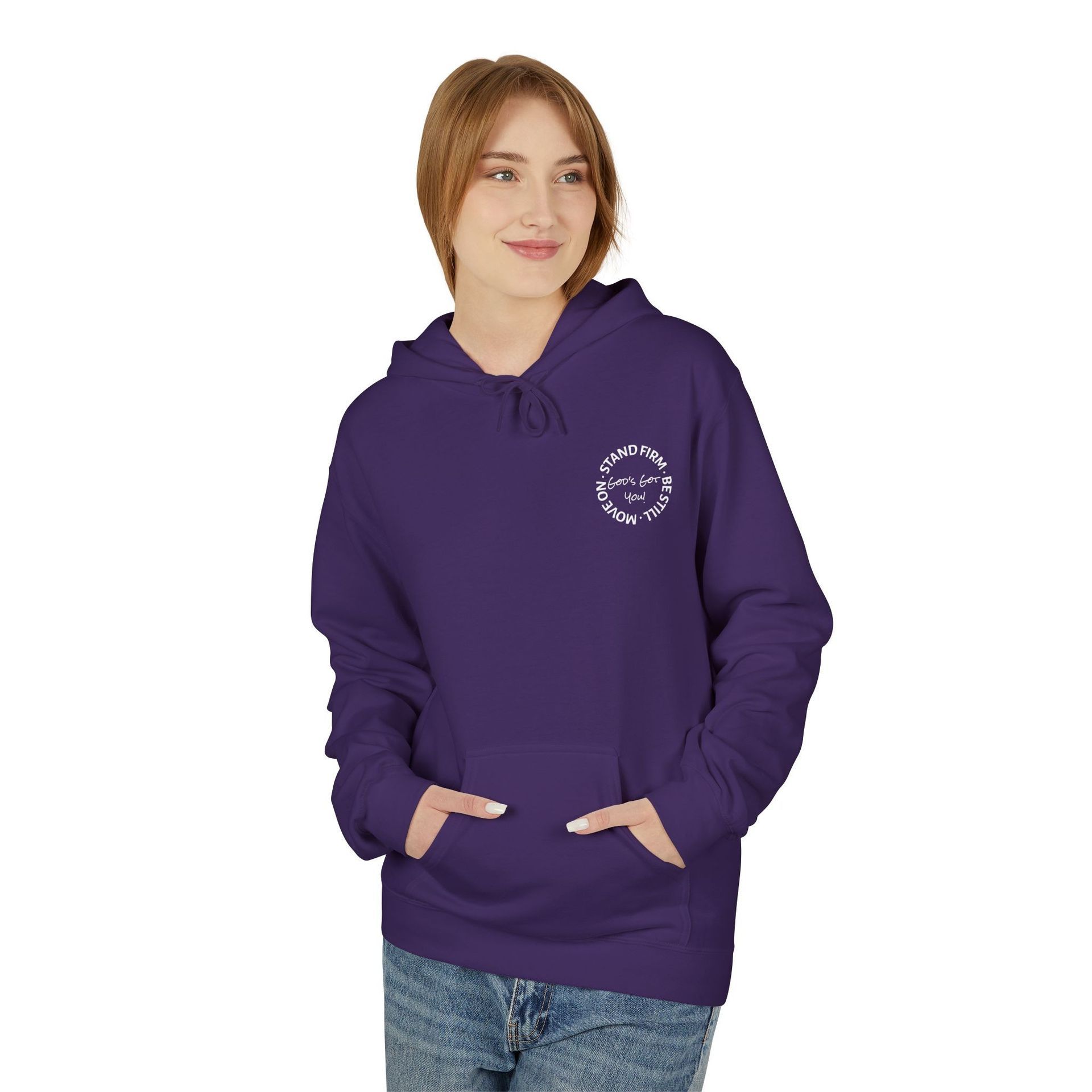 Woman in a purple hoodie with white graphic on chest, hands in pockets, looking to the side.