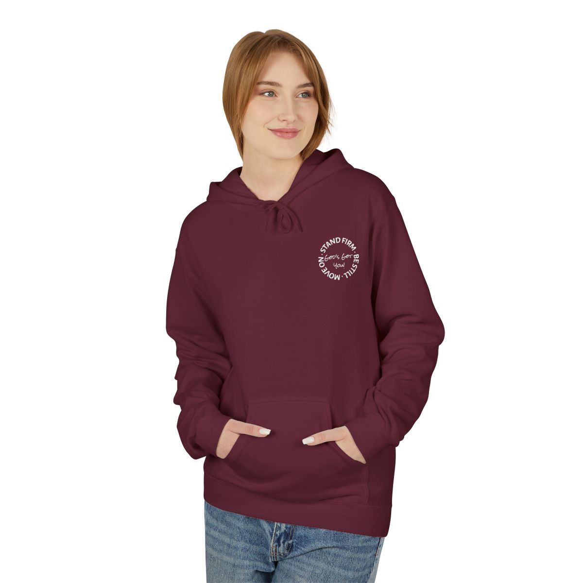 Woman in a burgundy hoodie and jeans smiles, hands in the front pocket, logo on the chest.