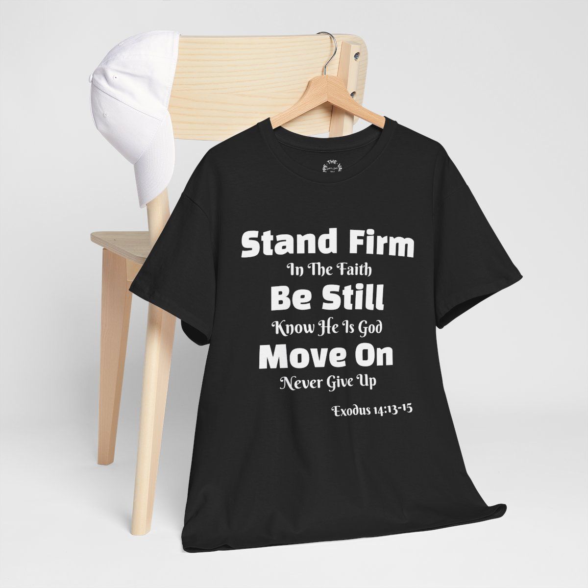 Black t-shirt with white text, hanging on a wooden chair. 