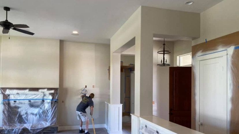 Person cleaning a light-colored kitchen with a mop beside a fireplace and cabinetry