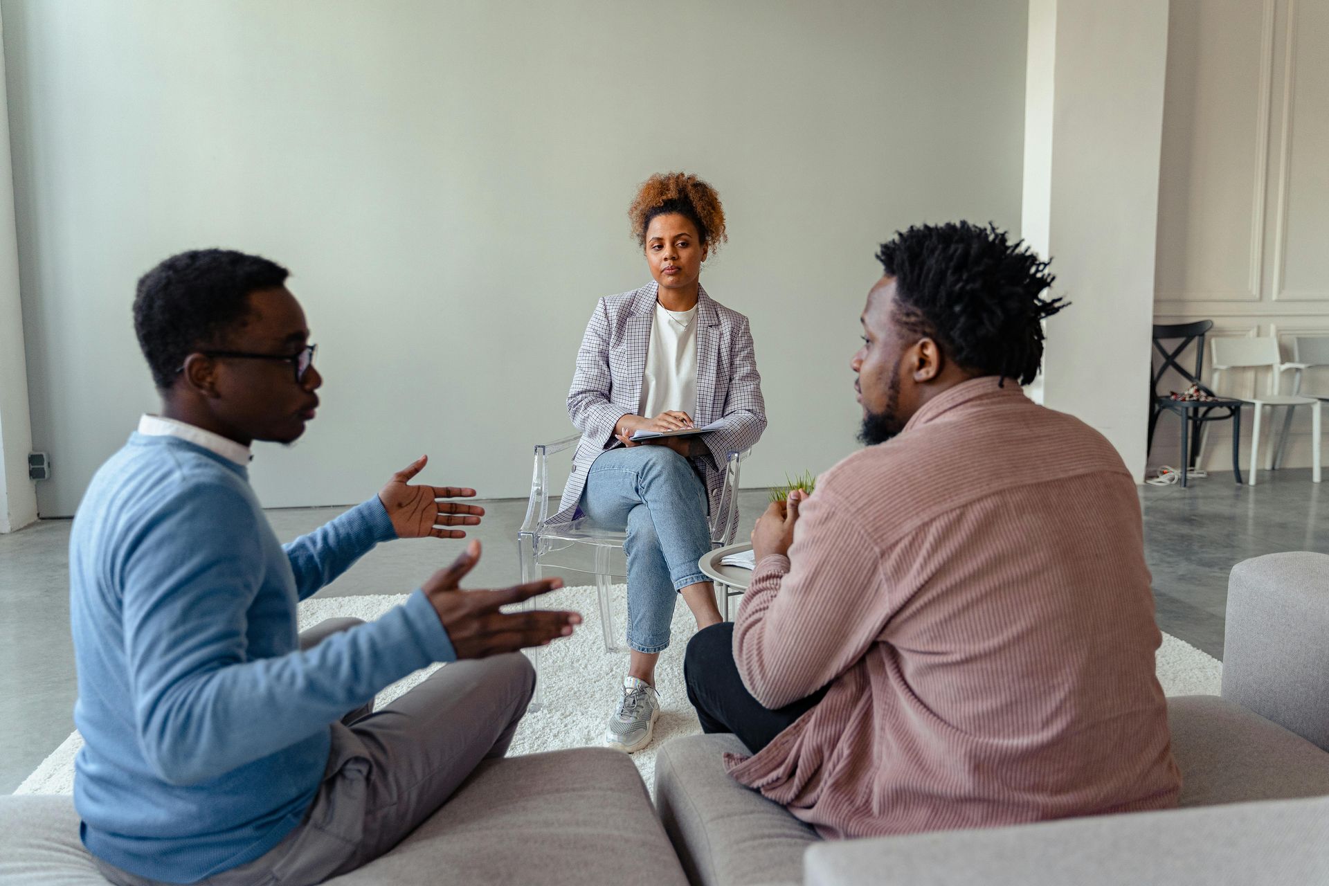 A group of people are sitting on a couch talking to a woman.