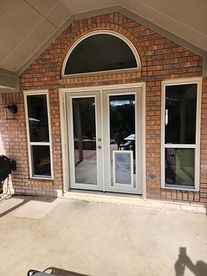 Brick home exterior with arched window, glass doors, dog door, and side windows.