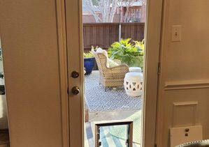 Interior view through glass door to a patio with outdoor furniture and a pet door.