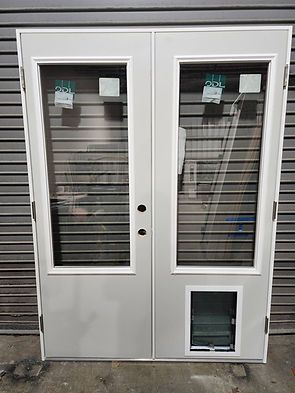 Double white door with large glass panels, a pet door, and a metal backdrop.