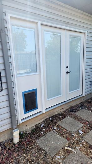 White French doors with sidelight, pet door, and blue trim, next to gray siding.