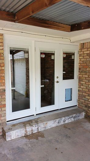 White French doors with dog door, on concrete step, under corrugated roof, brick exterior.