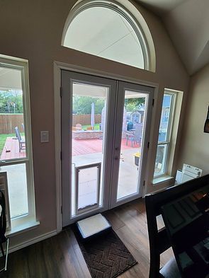 Interior view of a door with a dog door and windows leading to a patio.