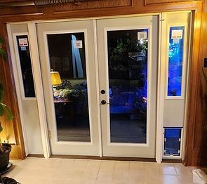 White French doors with sidelights. Pet door installed in the right sidelight. Interior setting, door open.