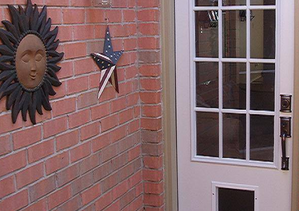 Brick wall with sun face decor, a star decoration, and a white door with glass panels.