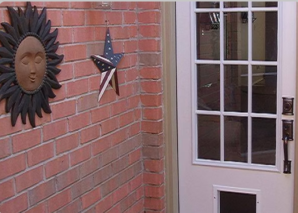 Brick wall with sun face decor and American flag star, next to a white door.